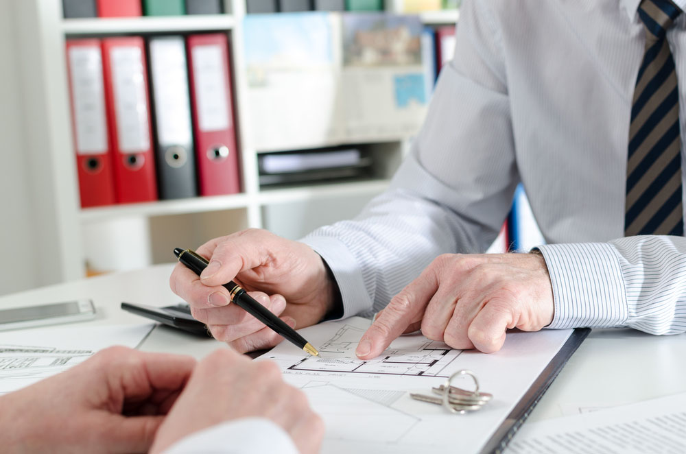 Realtor giving explanations to his client at the estate agency